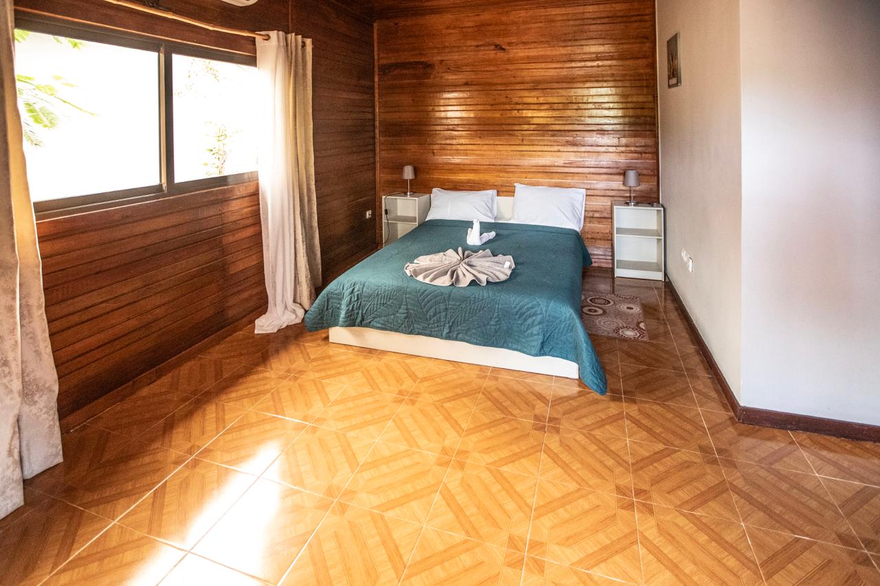 Quarto de casal com paredes em madeira e colcha verde