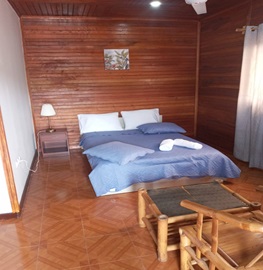 Quarto com colcha azul e mobiliário em bambu